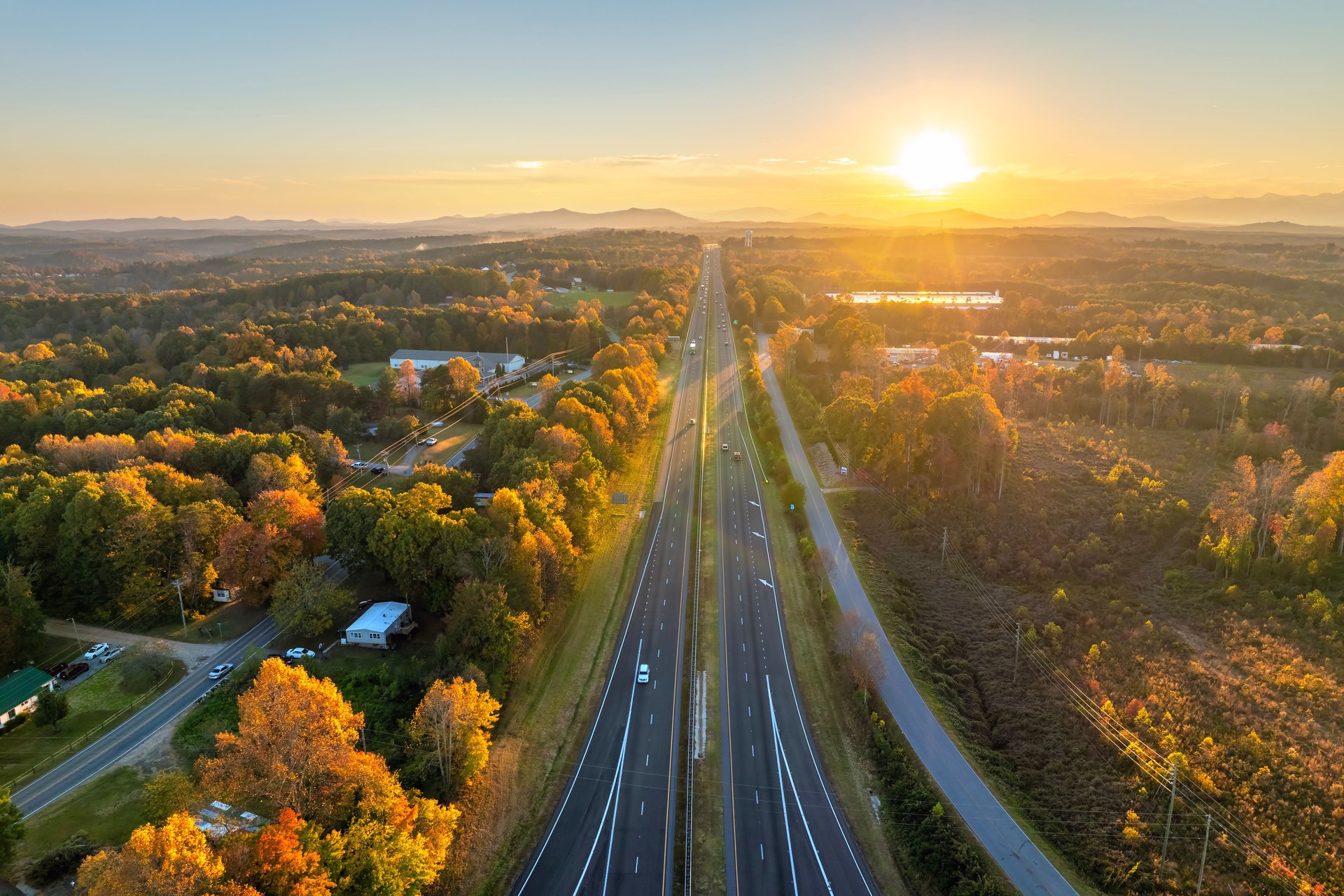 Wide multilane highway road in USA with fast driving cars at sunset. Above view of American transportation infrastructure